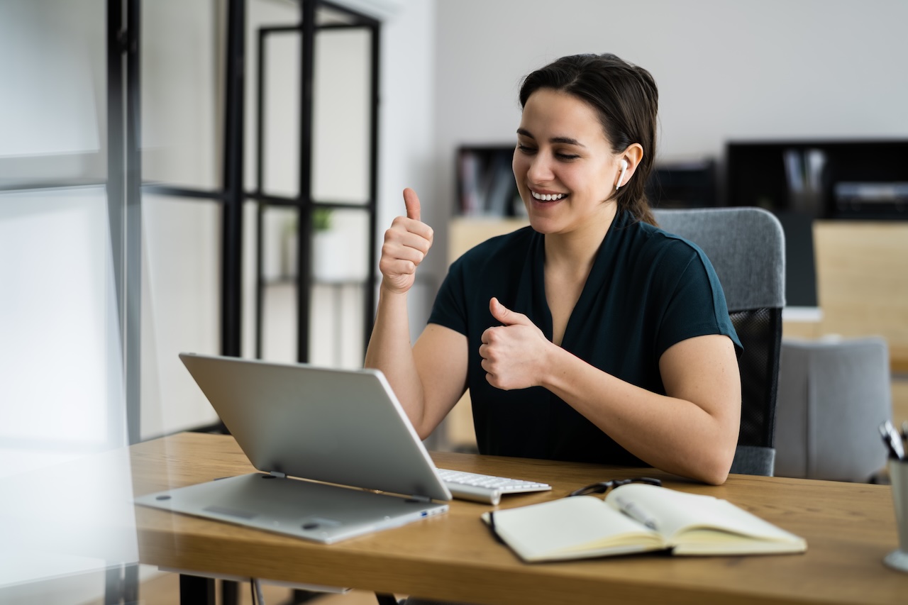 Frau telefoniert lachend am Laptop